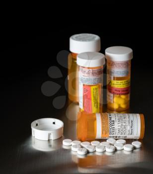 Oxycodone is the generic name for a range of opoid pain killing tablets. Prescription bottle for Oxycodone tablets and pills on metal table for opioid epidemic illustration