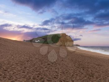 Sunrise on the beach underneath the cliffs and headland at West Bay in Dorset. This was used as the location for the Broadchurch TV series
