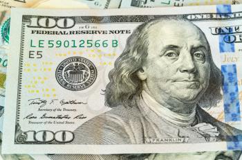 New design of US currency one hundred dollar bills laid out on table with focus on Ben Franklin portrait