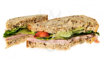 Isolated image of an english ham lettuce and tomato sandwich with a bite out of one corner. Bread is artisan multigrain wheat. Second sandwich is behind the first