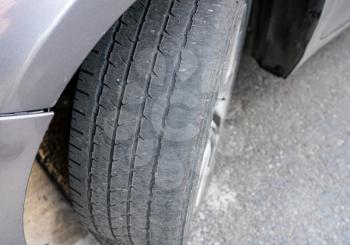 Front wheel tires or tyres on car badly worn and bald because of poor tracking or alignment of the wheels