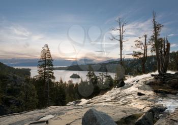 Sunrise at Emerald Bay on Lake Tahoe from the top of Lower Eagle Falls with a cross formed from aircraft trails appears to be a vision.
