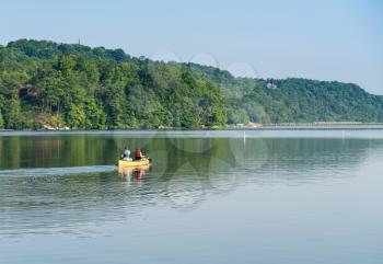 Male and female caucasian couple paddling a yellow canoe on a very calm morning on tree lined lake