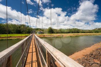 View along the narrow famous wooden suspension swinging bridge to cross the river in Hanapepe Kauai