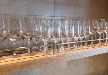 Shelf of wineglasses of difference shapes in bar or restaurant