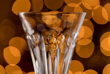 Bokeh lights from Christmas tree behind champagne crystal glass with focus on heart