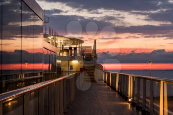 Reflections of the sunset in the windows of a modern cruise ship at dusk
