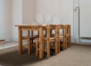 Eye level view of a wooden table and six chairs sized for children in classroom or play group