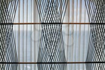 Net curtains covering a modern window with pattern from woven rope cords