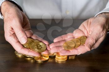 Senior man holding gold coins alongside stack of bitcoins to illustrate investment choice