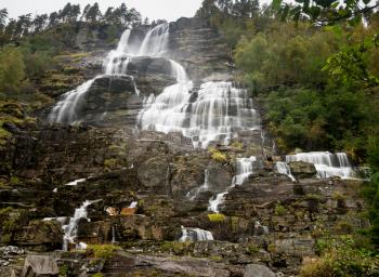 Cascades of water fall down hillside at Tvindefossen waterfall near Voss in Norway