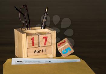 Wooden letters in calendar with Form 1040 income tax for 2017 showing tax day for filing is April 17 2018