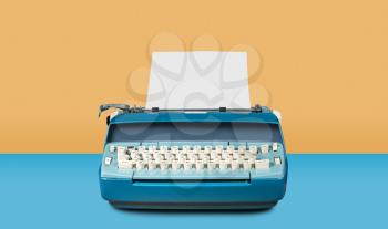 Modern electric typewriter on blue desk background with copy space