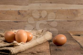 Easter background with brown organic eggs arranged on burlap sack on rustic wooden table