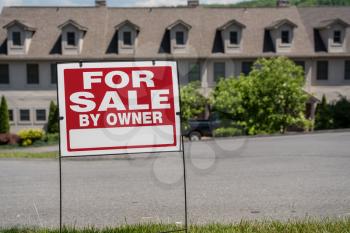 Blank for sale by owner sign in front of a row of town houses or homes in the USA