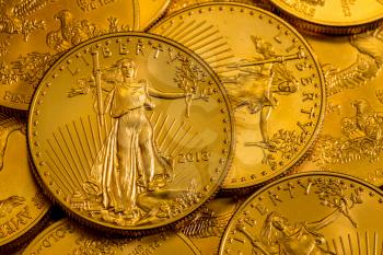Pile of golden coins with Liberty on US Treasury issue Gold Eagle one ounce pure gold coin