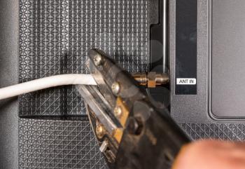 Close up of senior caucasian man hand cutting the aerial connection to his TV to illustrate cutting the cable TV cord
