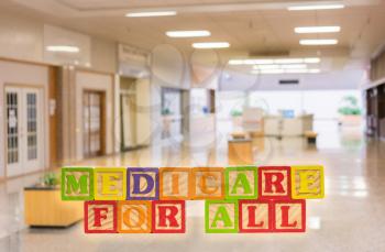 Medicare for All political policy for health insurance in wooden blocks against hospital background