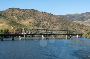 Vineyards line the hillsides as the railway bridge cross the river Douro with just enough headroom for the boat to pass