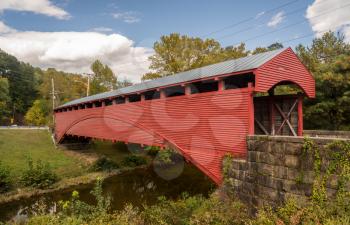 Well maintained Burr Truss covered bridge in Barrackville West Virginia crossing stream in the fall