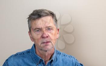 Head and shoulders portrait of a senior caucasian man unshaven and facing camera