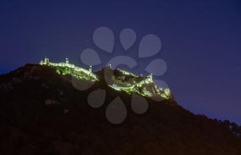 Evening view of the Moorish fortress on the hilltop above the city of Sintra illuminated at night