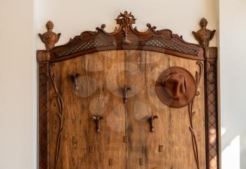 Old fashioned wooden hat, coat and umbrella stand in hallway on marble floor
