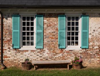 Simple blue shutters around white windows against a brick wall in colonial house in Virginia
