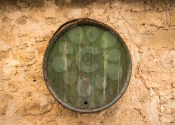 Old wooden barrel on stone farmhouse wall