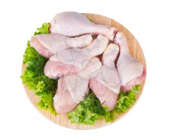 Raw chicken legs with green salad on a wooden board