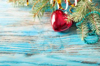 Red Christmas decorations and fir branch on a blue wooden background