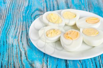 Boiled hen eggs in a white plate on a blue wooden background