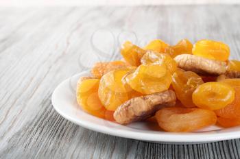 Dried fruits in white plate on a wooden background. Lemons, apricots and figs. 