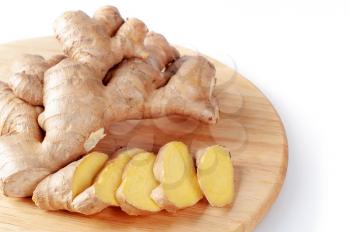 Fresh sliced ginger root on a round cutting board. Healthy food and spices.