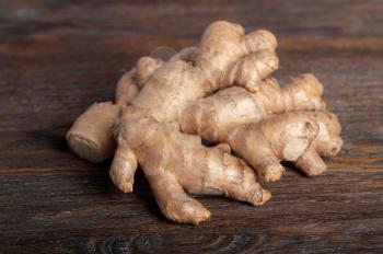 Fresh ginger root on a dark brown wooden table. Healthy food and spices.