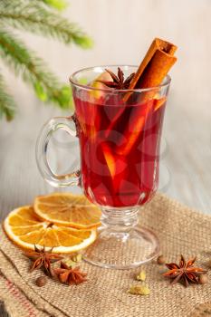 Mulled wine with spices and fruit on a wooden table. Christmas hot drink with red wine, oranges and cinnamon. Tradition holiday menu.