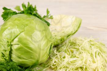 Fresh white cabbage, chopped cabbage and green vegetables for salad on a wooden background. Vegetarian and healthy diet food concept. 