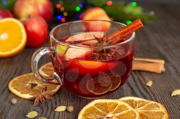 Mulled wine with spices and fruit on a brown wooden table. Traditional Christmas hot drink with red wine, apples, oranges and cinnamon. Holiday food and drink