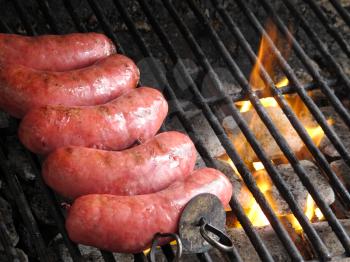 Grilled sausages on grill, with smoke above it