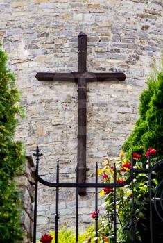A large wooden cross on the stone wall of the Greek Catholic church behind a metal fence