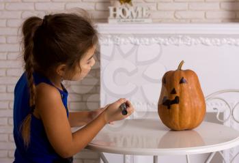 The little girl is preparing to celebrate Halloween and decorate pumpkins