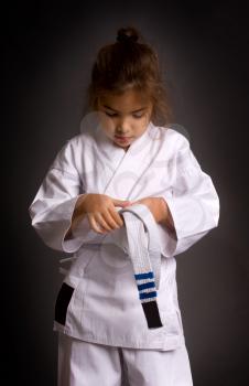 Little girl karatek tie a belt with three deserved stripes