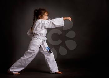 A little girl karate in a white belt, but already received three patches performs kata