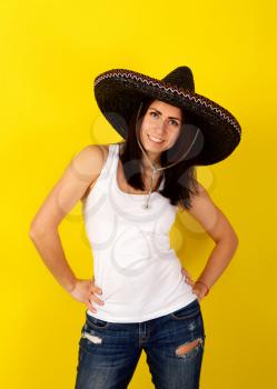 Young pretty girl in classic Mexican sambrero on a bright yellow background