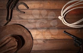 Old classic wooden background from the symphols of the cowboy wild west. Lasso, hat, revolver and horseshoe with space for text