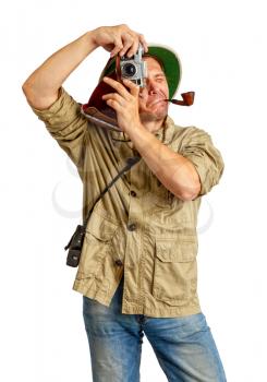 Adult Tourist in a tropical cork helmet and protective clothing with a pipe in his mouth photographs something on the old camera