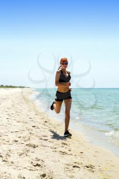 young girl in sportswear jogging on a deserted sea coast