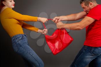 the girl is trying to prevent the robber who wants to pull the bag out of her hands