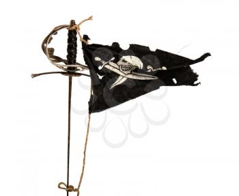 Black pirate flag winding up in the wind tied with a rope to an old sword