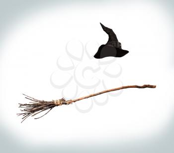 classic pointed witch hat and flying broom flying on a white background